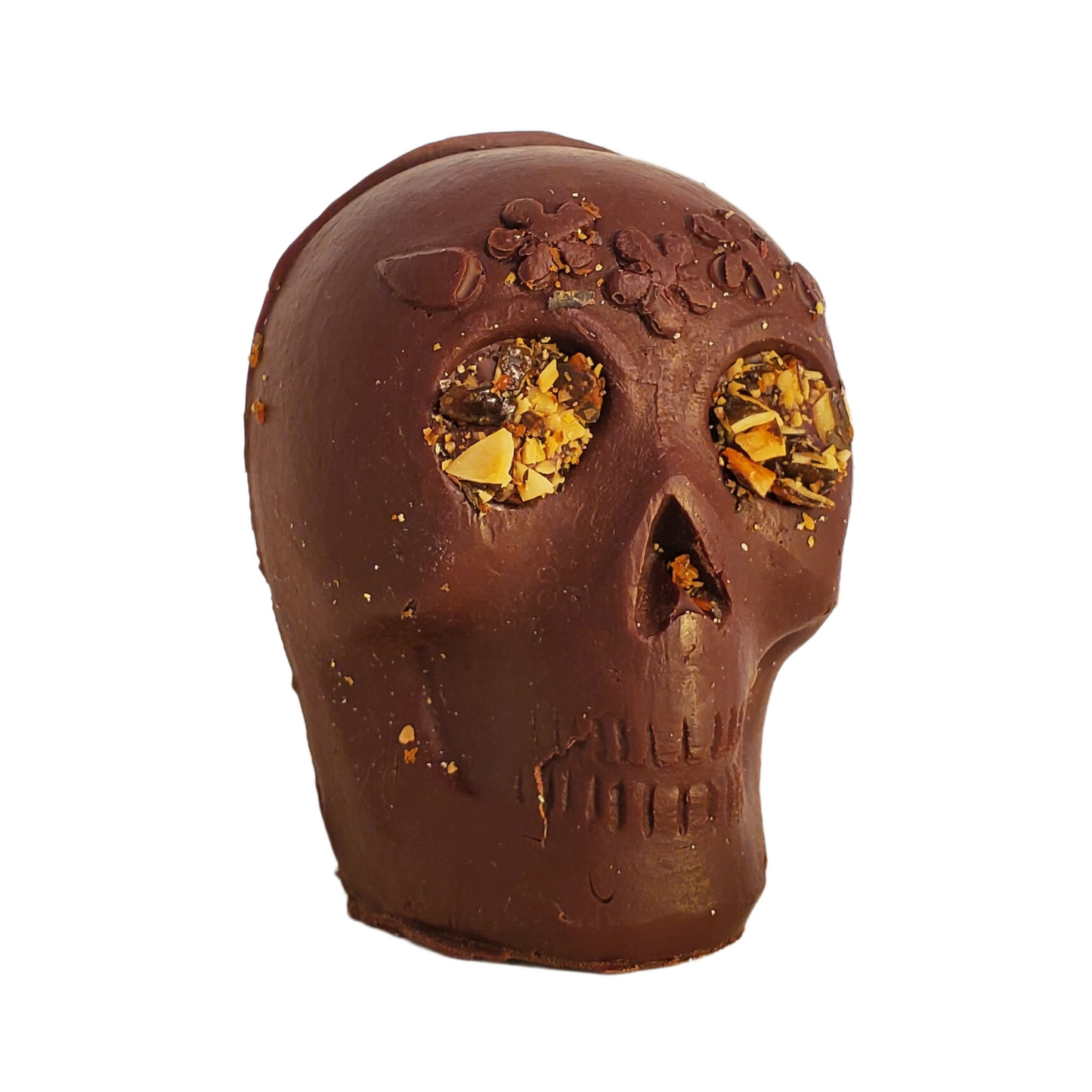 Chocolate skull figurine with pumpkin seed eyes and flower headband decoration.