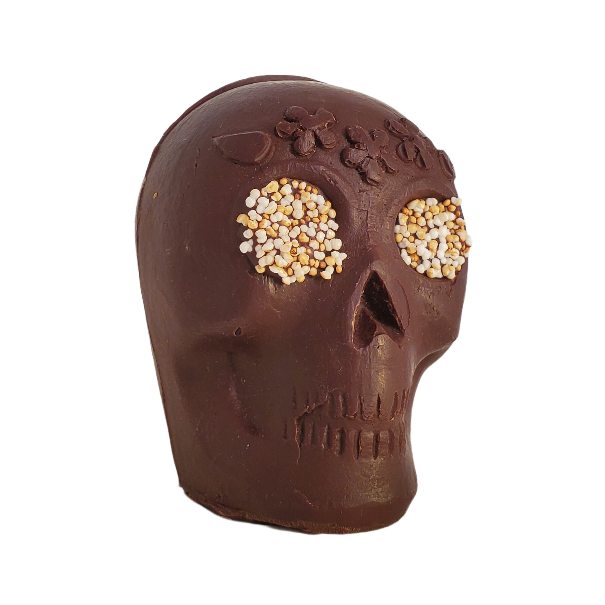 Chocolate skull figurine with white popped amaranth eyes and a flower headband decoration.