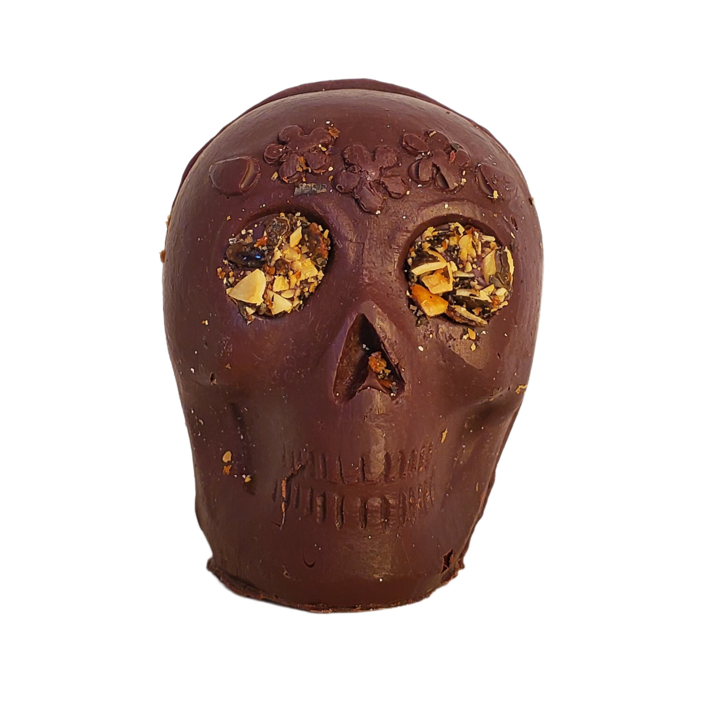 Chocolate skull figurine with pumpkin seed eyes and flower headband decoration.